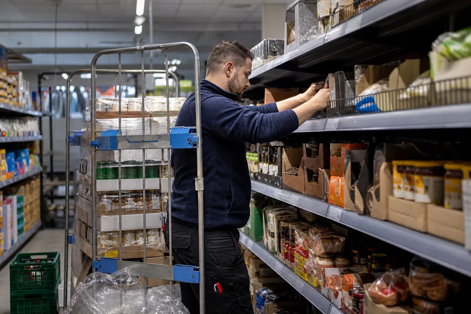 Pracownik uzupełnia półki supermarketu przed otwarciem